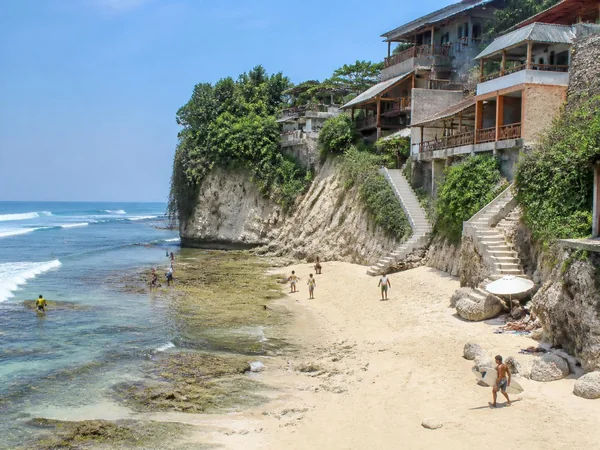 Cliffside guesthouses and stone stairways above the small reef beach at Bingin